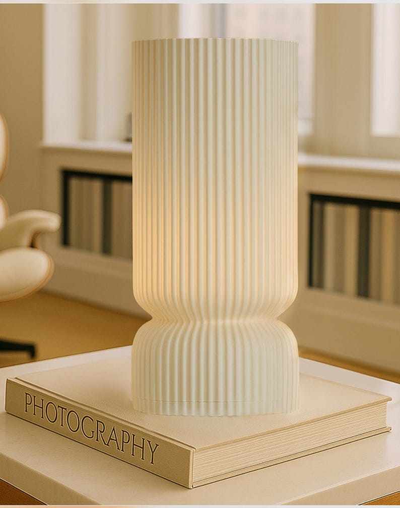White ribbed vase on a book titled 'Photography' in a softly blurred indoor setting