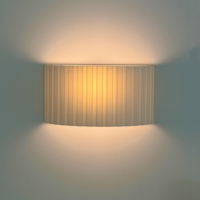 Wall-mounted lamp with a ribbed beige shade on a plain wall.