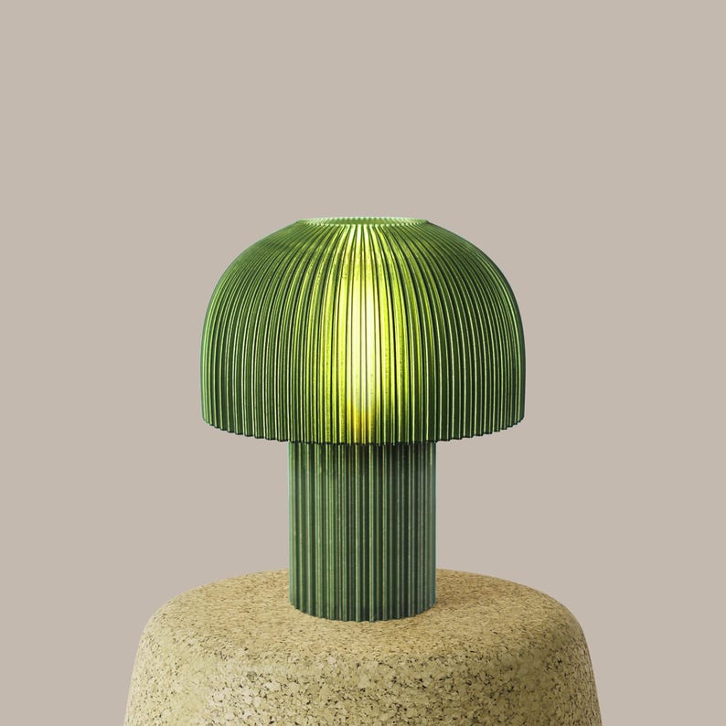 Green pleated table lamp on a beige surface with a neutral background