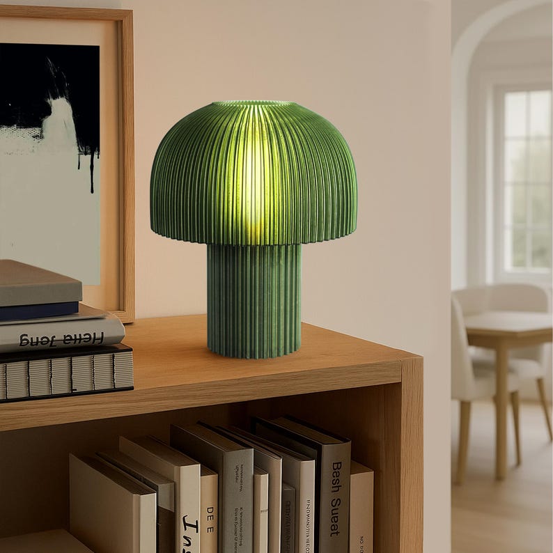 Green ribbed table lamp on a wooden shelf with books in a room setting